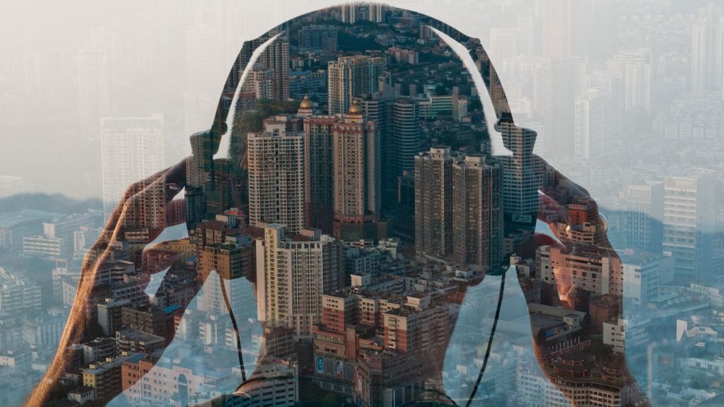 Guy using Headphones, looking at the city from a skyscraper